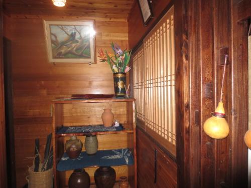 Amami skeptical inn - Vacation STAY 14029v في Akina: غرفة بجدران خشبية ورف مع مزهريات