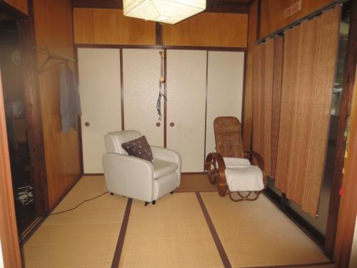 een woonkamer met een stoel en een kruk bij Amami skeptical inn - Vacation STAY 14029v in Akina