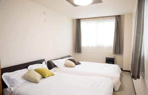 two beds in a room with white sheets and yellow pillows at STAY IN TOKIWA - Vacation STAY 16336v in Asahikawa