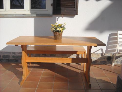 a wooden table and bench with a vase of flowers on it at Casa Alice in Locarno