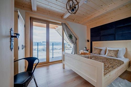 a bedroom with a large bed with a large window at Eco dom z sauną- Pasja II View,Lake & Ski in Kluszkowce