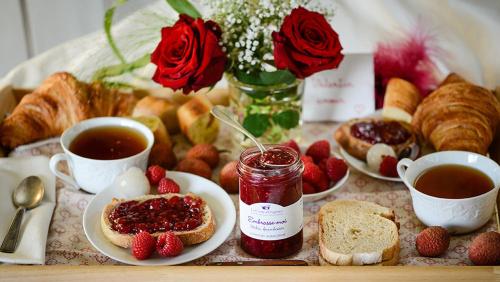 a table topped with cups of tea and strawberries and pastries at Un je ne sais quoi de Paradis in Les Vans