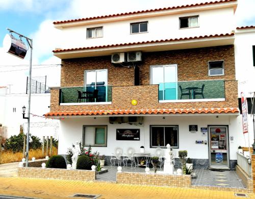 un edificio con balcón con mesas y sillas en Hostel Boutique Marisol en Monte Gordo