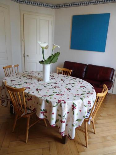 a table with a vase with a flower on it at Meublé de tourisme in Frasne