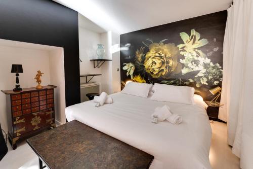 a bedroom with a large white bed with a painting on the wall at Le Balcon du Palais de l'Isle - Aprtement 4 with stunning views in Annecy