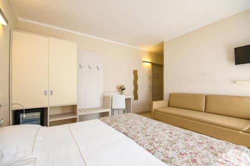 une chambre avec un lit blanc et un canapé dans l'établissement Locanda Corte Montioni, à Lazise
