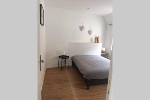 Un dormitorio con una cama en una habitación blanca. en Maison bord de Mer, en Bernières-sur-Mer