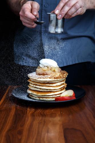 a person is preparing a stack of pancakes on a plate at Fairmont Hotel Vancouver in Vancouver