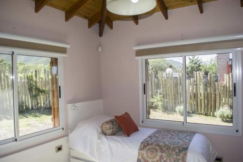 a bedroom with a bed and two large windows at Cabañas Juan Pedro in Los Molles