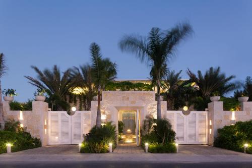 una casa blanca con una puerta y palmeras en Villa Sha - Cancun Beachfront, en Cancún