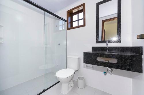 a bathroom with a toilet and a glass shower at Casa Patta - 05 dormitórios, com piscina. in Bombinhas