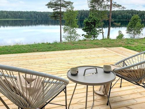 2 Stühle und ein Tisch auf einer Holzterrasse mit einem See in der Unterkunft 9 person holiday home in H CKSVIK in Håcksvik