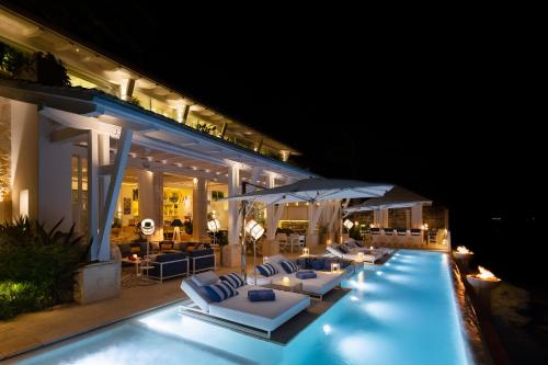 a pool with lounge chairs and umbrellas at night at Villa Sha - Cancun Luxury Beachfront in Cancún