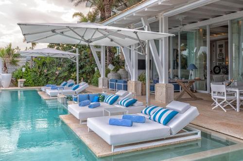 a pool with lounge chairs and an umbrella at Villa Sha - Cancun Luxury Beachfront in Cancún