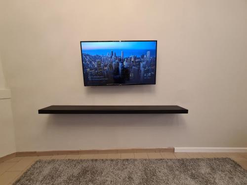 a flat screen tv on a wall with a shelf at Chaleureux bel Espace - Confort et Harmonie in Liège