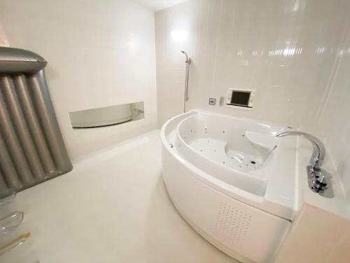 a white bathroom with a tub in a room at リージェンシー in Takata
