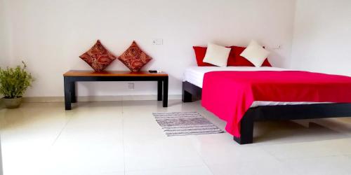 a bedroom with a bed with a red blanket and a table at Mitrayu in Nugegoda