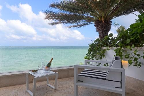 a white chair and a table and a palm tree at Villa Sha - Cancun Luxury Beachfront in Cancún