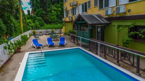 una piscina con sillas azules y un edificio en Pineapple Court Hotel, en Ocho Ríos