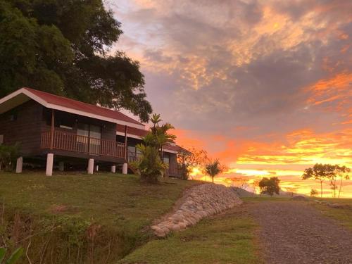 uma casa numa colina com um pôr-do-sol ao fundo em Cabañas Bambú em San Vito