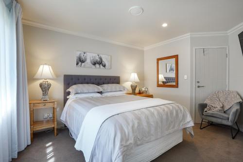 1 dormitorio con 1 cama grande y 1 silla en Ambience on Pacific B&B, en Palmerston North