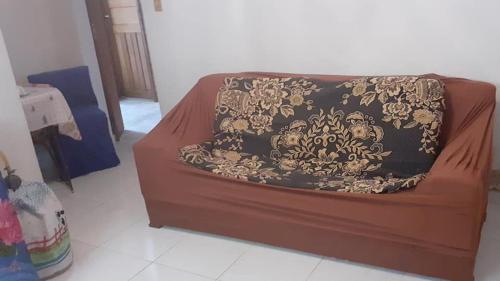 Un sofá marrón con una manta negra y dorada. en Pousada Sro Adilson en Mangaratiba