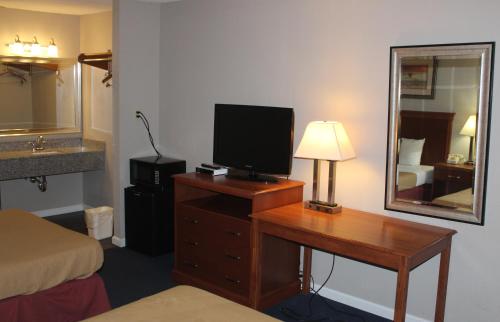 een hotelkamer met een bureau, een televisie en een spiegel bij Interstate Motel in Rensselaer