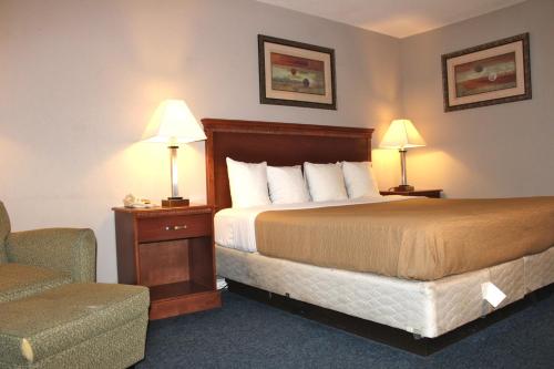 Habitación de hotel con cama, silla y lámparas en Interstate Motel, en Rensselaer