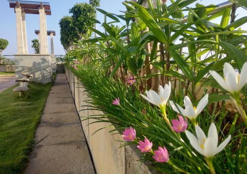 a stone fence with pink and white flowers at Grand Gardenia in Tiruchchirāppalli