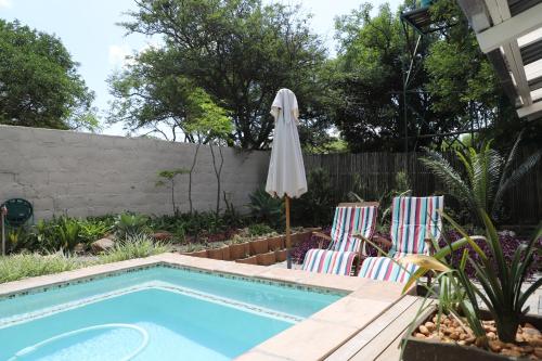 a swimming pool with two chairs and an umbrella at Memories Made Cottage in Kampersrus AH
