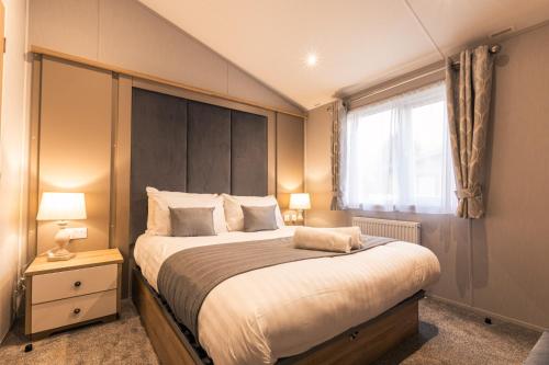 um quarto com uma cama grande e uma grande cabeceira. em The Haven Lodge with Hot Tub em York