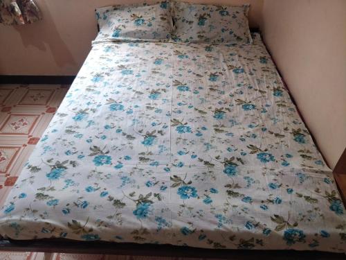 - un lit avec une couette blanche et des fleurs bleues dans l'établissement Shree Samarth Farmhouse, à Murud