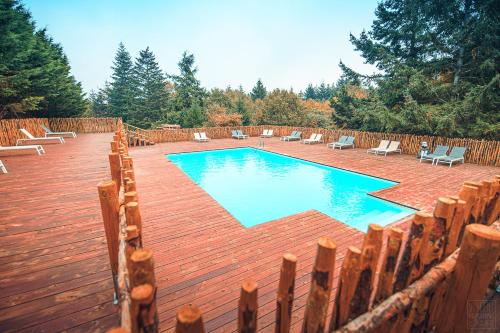 a swimming pool with chairs and a wooden fence at Domaine de la Vitarelle Glamping in Villanière