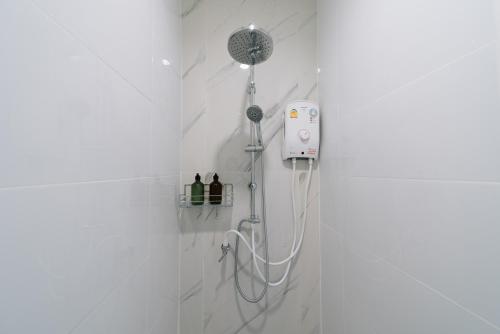 a shower in a white tiled bathroom with a shower at Stayokay Sattahip - Flat House in Sattahip