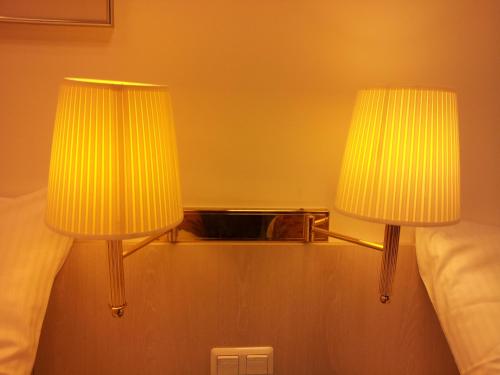two lamps on a shelf next to a bed at Hotel New Fair Munich Messe in Munich
