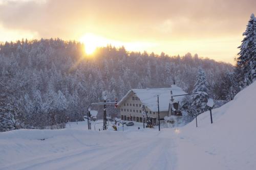 a ski lodge in the snow with the sun setting at K's House Hokkaido - Asahidake Onsen Hostel in Higashikawa