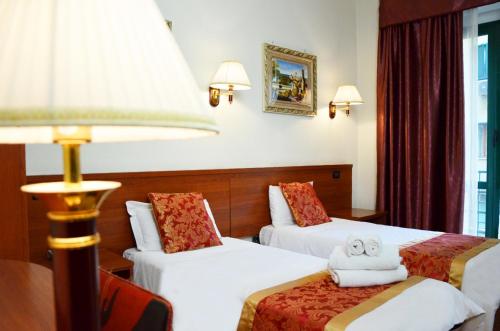 una camera d'albergo con due letti e una lampada di Hotel Geo a Roma