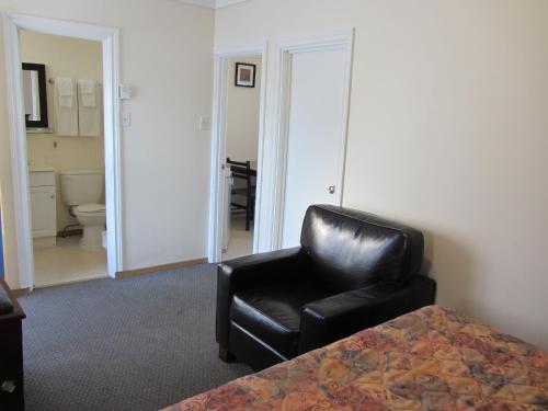 a black leather chair in a room with a bathroom at The Maplewood Motel in Port Elgin