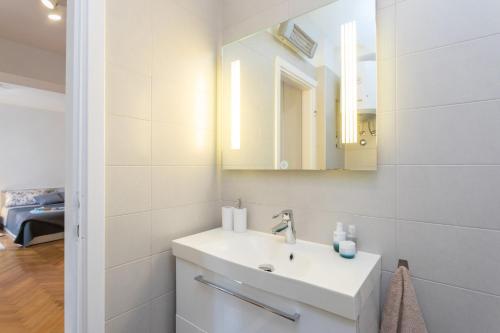 ein weißes Badezimmer mit einem Waschbecken und einem Spiegel in der Unterkunft Luxury BonBon next to Banje beach and Old Town, great location in Dubrovnik