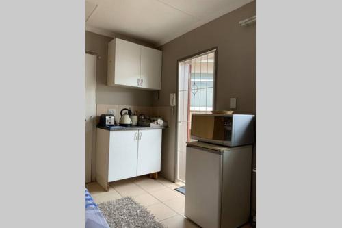 una piccola cucina con armadietti bianchi e forno a microonde di Cozy guest suite with private access a Roodepoort