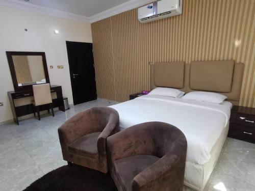 a bedroom with a large bed and two chairs at Address hotel Apartments العنوان للشقق الفندقية in Aş Şa‘arah