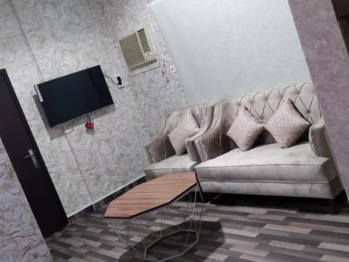een woonkamer met een bank en een flatscreen-tv bij Iwaa Alkharj Apartments in Al Kharj
