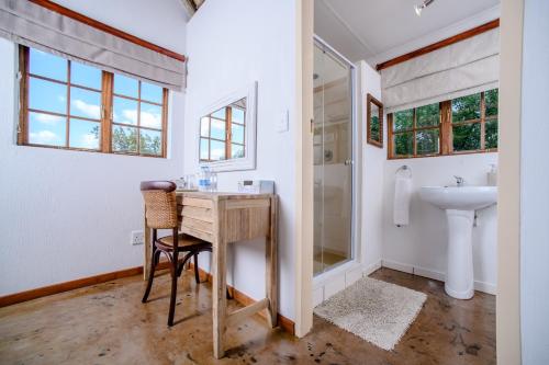 a bathroom with a desk and a sink and a shower at Needles Lodge in Marloth Park