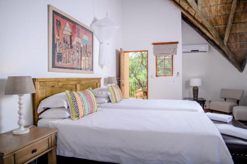 um quarto com 2 camas brancas e uma mesa em Needles Lodge em Marloth Park