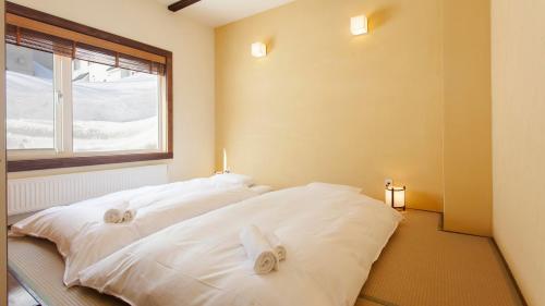 a bedroom with two white beds and a window at Ginsetsu in Kutchan