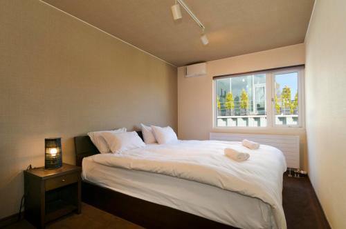 a bedroom with a large white bed with a window at Sugarpot in Kutchan