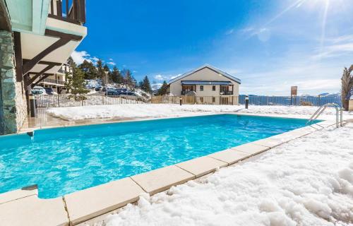 uma piscina coberta de neve em frente a uma casa em Charmant studio face aux Pyrénées em Font Romeu Odeillo Via