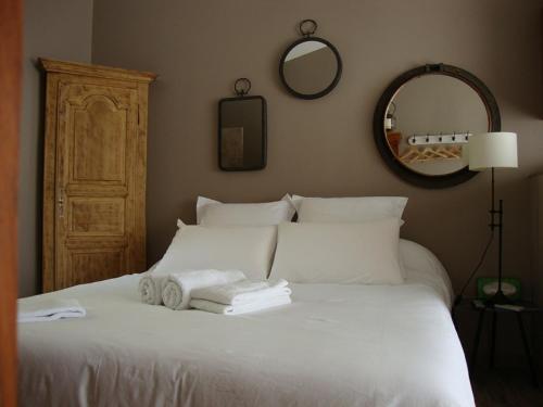 Un dormitorio con una cama blanca con toallas. en Gîte Les Roseaux Spa extérieur privatif inclus, en Moussan