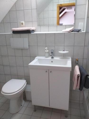 a white bathroom with a toilet and a sink at Pension Töpferhof in Bad Berka