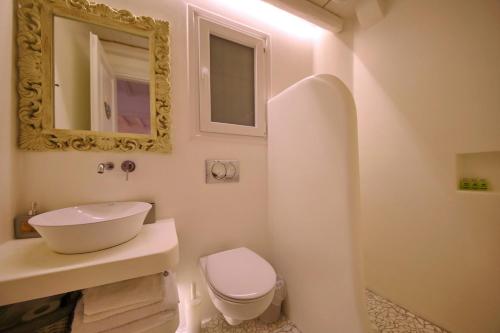 a bathroom with a sink and a toilet and a mirror at Evlalia Studios & Villas in Skopelos Town
